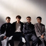 Four men sat down staring at the camera.